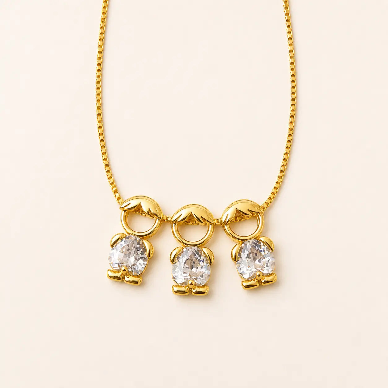 Gold-tone necklace with three boy figure pendants and white stones