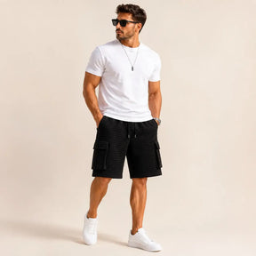 Man wearing black Koven waffle cargo shorts with a white T-shirt