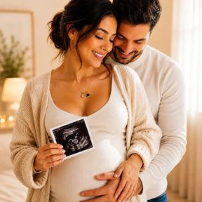 Expectant mother wearing the Mother & Child Love Necklace while holding an ultrasound photo with her partner
