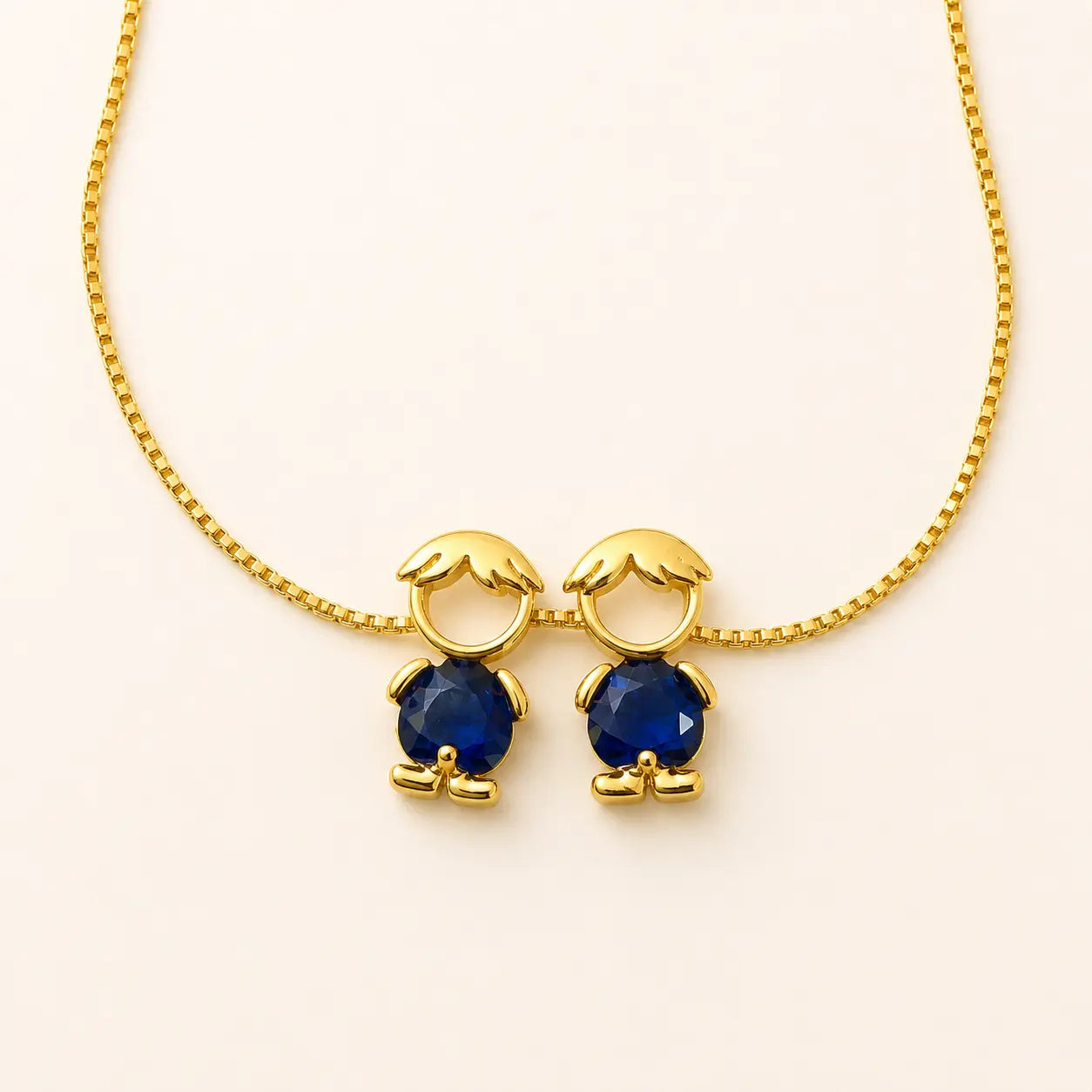 Gold-tone necklace with two boy figure pendants and blue stones