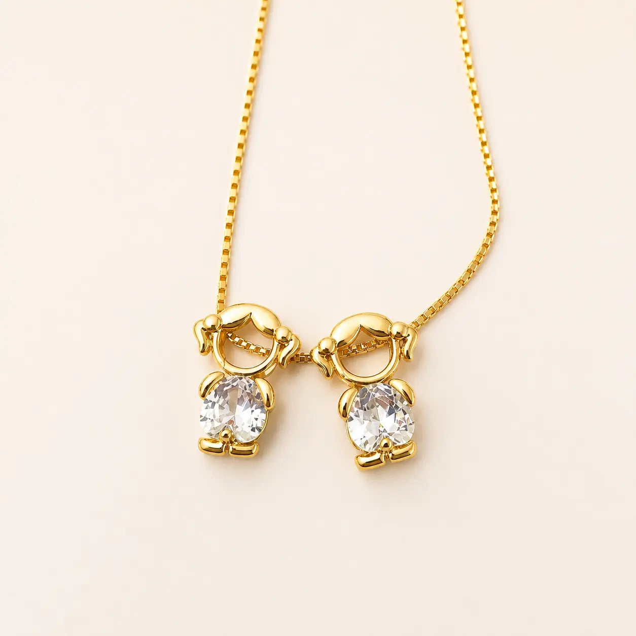 Gold-tone necklace with two girl figure pendants and white stones