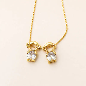 Gold-tone necklace with two girl figure pendants and white stones